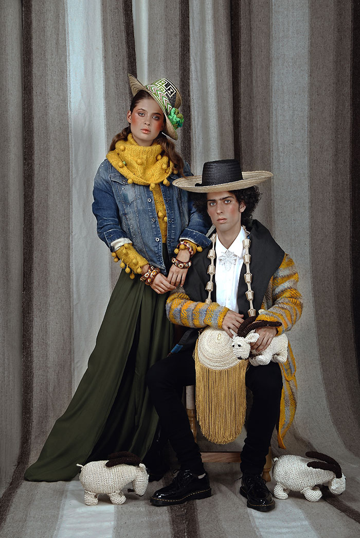 Alejandra con un suéter amarillo de seda, del diseñador textil Edue Marcial Pérez, de Yopal. Brazaletes barnizados de la Casa del Barniz de Pasto; sombrero del Centro Temático del Sombrero Wayúu; pantalón de Puntamar y chaqueta denim de G-Star. Tomás lleva un sombrero Wayúu elaborado por el artesano Gary González; con un gabán de lana y seda de Edue Marcial Pérez sobre una guayabera de lino bordada a mano en Cartago, de Eliseo Gutiérrez; complementada con broche de filigrana del maestro Eligio Rojas y poncho de Adriana Santacruz, de Pasto. El bolso, elaborado en palma de iraca y flecos de acrílico con pompones forrados en hilo de seda, es de Palma Canaria. Jean negro de Orozco Clothing; zapatos charolados de Dr. Martens. Chivos tejidos en cabuya por artesanos de Santander en el Laboratorio de Innovación y Diseño de Artesanías de Colombia.